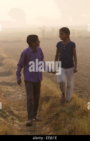 India, Uttar Pradesh, Agra, brother and sister holding hands walking in field Stock Photo