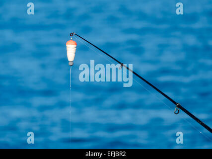 Fishing Bait-Rod with Float against the Blue Sea Water Surface, closeup Stock Photo