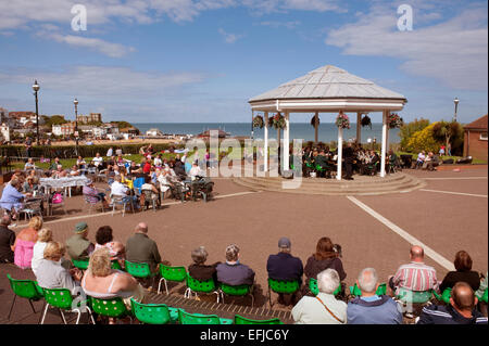 People sit around watching a concert at the Bandstand at Broardstairs in Kent. On a summers day. Stock Photo