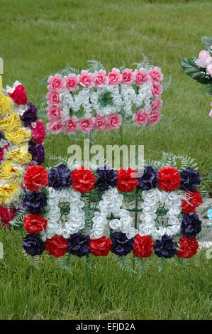 Plastic memorial flowers at cemetery. Stock Photo