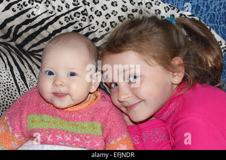 two little babies sisters lying on the bed and smiling Stock Photo