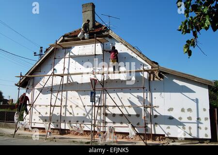 Masters of the construction scaffolding in the morning carry out works on the facade of the house. Stock Photo