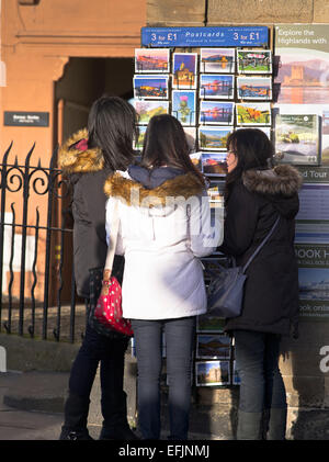 dh  OLD TOWN EDINBURGH Asian girl tourists selecting postcards tourist postcard stand scotland souvenir Stock Photo