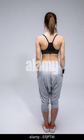 Back view portrait of a young woman in sports wear over gray background Stock Photo