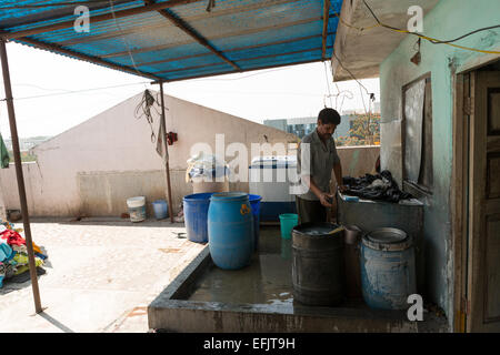 Indian man washing clothes on a rooftop Stock Photo