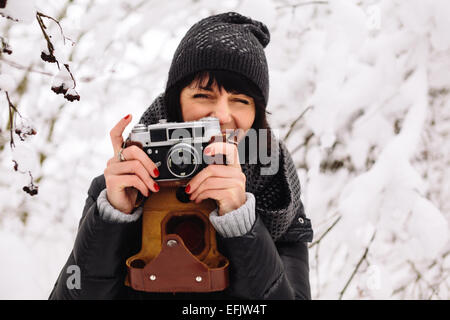 smiling girl photographed on a camera in winter forest Stock Photo