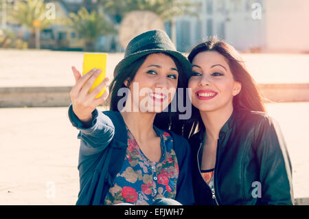 Friends having fun in city taking selfie sitting on a staricase two friends taking selfie with a filter applied instagram style  Stock Photo