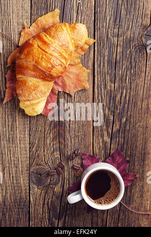 Cup of hot coffee and croissant on vintage wooden table. Top view Stock Photo