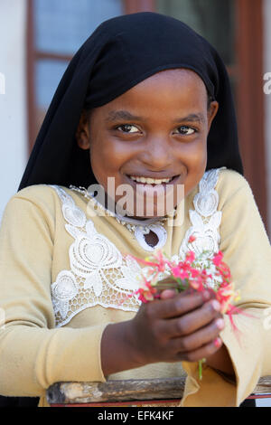 Kenya, ten year old girl wearing a veil and holding hibiscus flower in her hand Stock Photo