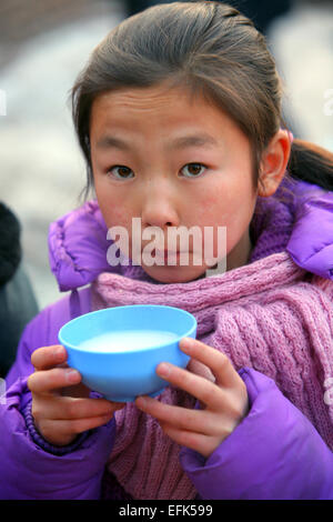 Girl drinking hot yak milk from a bowl, Ulanbaator, Mongolia, Asia Stock Photo