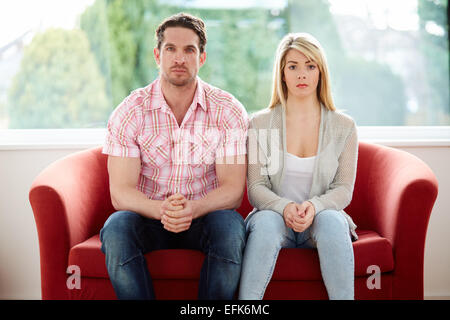 Couple sat together on sofa Stock Photo