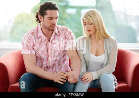 Couple sat together on sofa Stock Photo