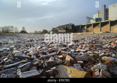 piles of rubble on derelict land and factory building covered by winter snow near selby yorkshire united kingdom Stock Photo