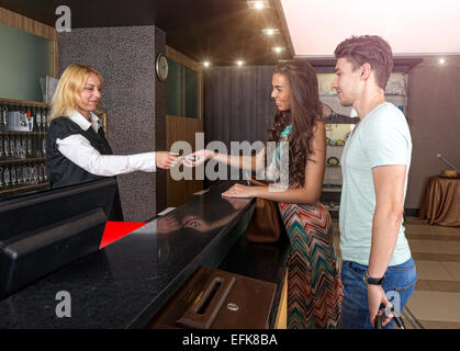 Receptionist - the hotel - give the young couple a room key Stock Photo