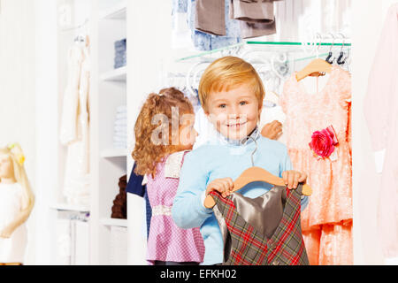 Boy with hanger and girl behind choosing clothes Stock Photo