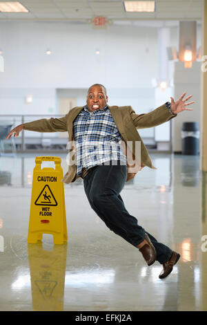 African American businessman slipping on wet floor inside office building Stock Photo