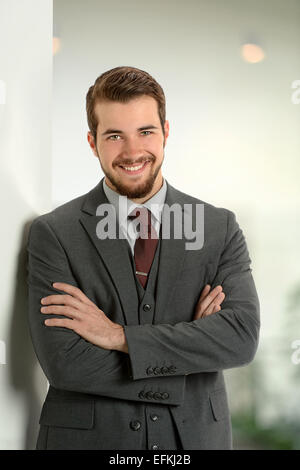 Portrait of young businessman leaning on office wall Stock Photo