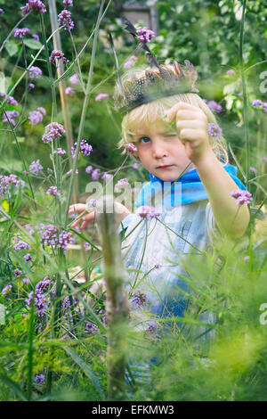 Boy dressed up and playing with plants in garden Stock Photo