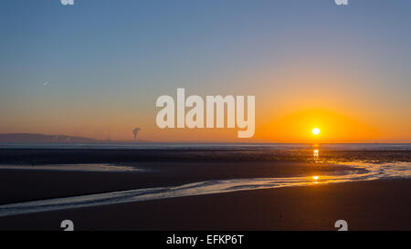 Sunrise over Swansea beach, South Wales, on a clear winter morning, with the industrial emissions from Port Talbot visible acros Stock Photo