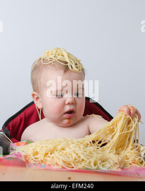 12 month old baby eating pasta Stock Photo