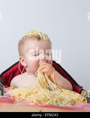 12 month old baby eating pasta Stock Photo