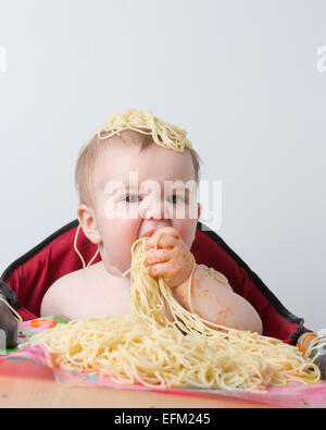 12 month old baby eating pasta Stock Photo