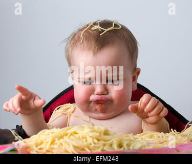 12 month old baby eating pasta Stock Photo