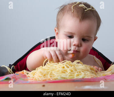 12 month old baby eating pasta Stock Photo