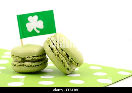 Happy St Patricks Day green macaron cookies with shamrock flag on white table. Stock Photo