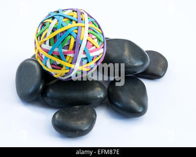 Ball of rubber bands on a pile of black stones Stock Photo