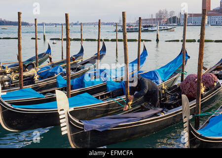 A gondolier preparing his gondola on the lagoon Venice Veneto Italy Europe Stock Photo