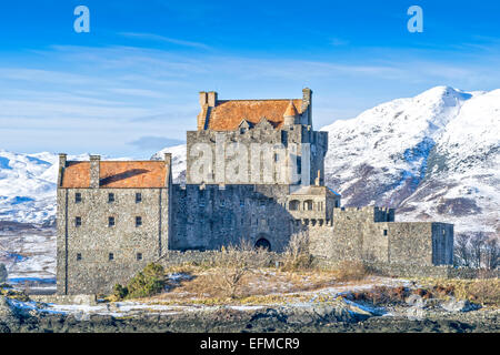 EILEAN DONAN THE CASTLE IN WNTER WITH A BLUE SKY AND HEAVY SNOW ON THE MOUNTAINS Stock Photo