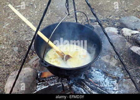 black pot on camp fire, cooking in big metallic cauldron outdoor Stock Photo