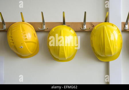 Two helmets hanging on coat hangers on a construction place Stock Photo