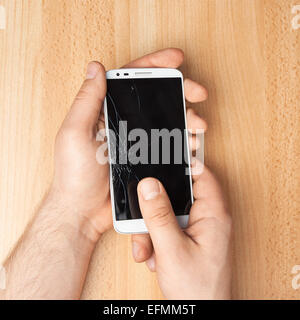 Hands holding a phone with a broken screen Stock Photo