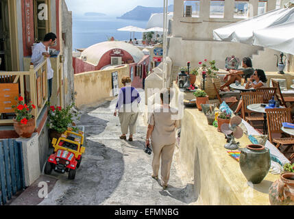 Santorini, Greece. 29th Sep, 2004. A pair of female tourists strolls past an outdoor restaurant and shops in the picturesque scenic village of Oia in Santorini. The southernmost member of the Cyclades island group, colorful Santorini is a favorite tourist and cruise ship destination. © Arnold Drapkin/ZUMA Wire/Alamy Live News Stock Photo