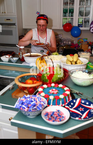 Caucasian female in her thirties serving herself at buffet lunch at home for 4th July Independence Day, USA Stock Photo