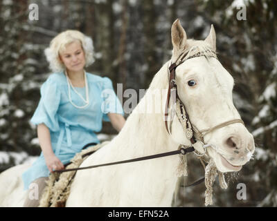 Attractive woman wearing blue dress and she riding a white horse, focus on horse eyes Stock Photo