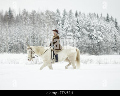 Attractive woman riding a white horse, winter landscape Stock Photo