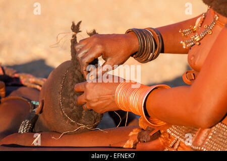 A Himba woman making traditional braids on a young girl, Namibia. Stock Photo