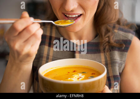 Closeup on young woman eating pumpkin soup in kitchen Stock Photo