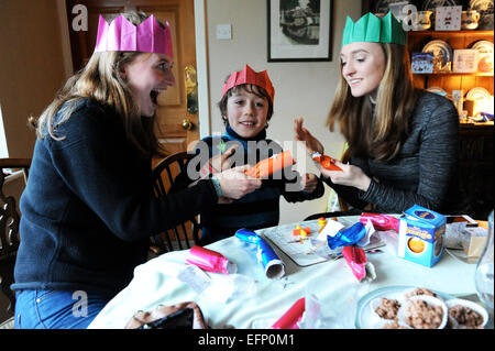 Three young cousins pulling crackers at the Christmas dinner table. Stock Photo