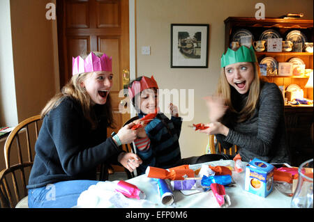 Three young cousins pulling crackers at the Christmas dinner table. Stock Photo