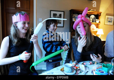 Three young cousins pulling crackers at the Christmas dinner table. Stock Photo