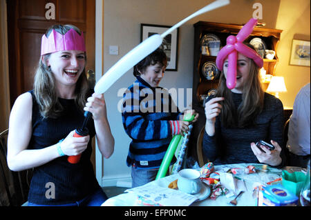 Three young cousins pulling crackers at the Christmas dinner table. Stock Photo