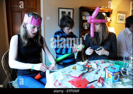 Three young cousins pulling crackers at the Christmas dinner table. Stock Photo