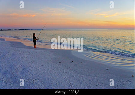 Boy fishing at sunset on Siesta Key Beach at Sarasota, Florida. Stock Photo