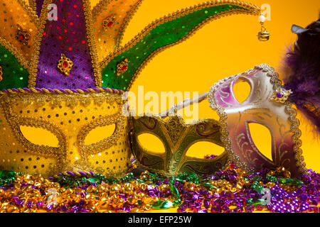 A festive, colorful group of mardi gras or carnivale mask on a yellow background.  Venetian masks. Stock Photo