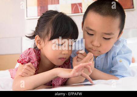 Boy and girl using tablet in bed Stock Photo