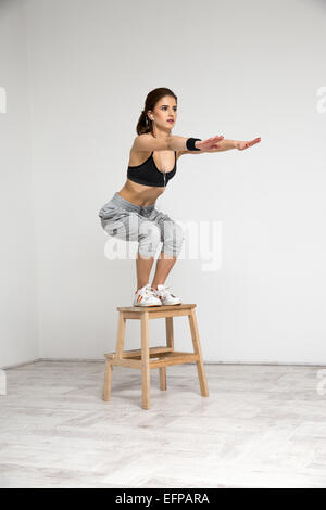 Young healthy woman doing squat exercises Stock Photo